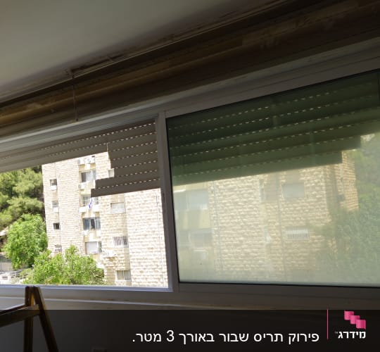 חלון עם תריסים פתוחים למחצה ונוף חיצוני